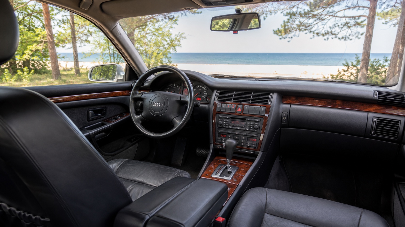 Audi A8 D2-interiør set fra højre bagsæde med analoge instrumenter og fabriksdisplay tændt